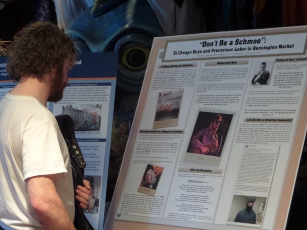 A Kensington Market resident reads a poster in which he is featured.